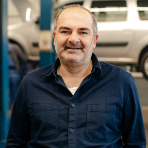 Rainer Sombetzki lächelt in der Autowerkstatt in die Kamera.