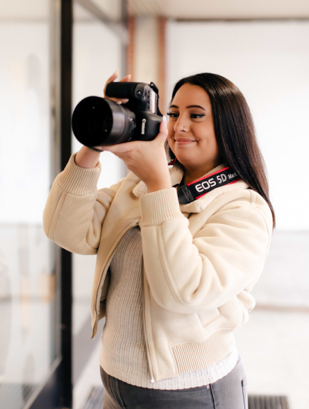 Eine junge Frau fotografiert mit einer Kamera.