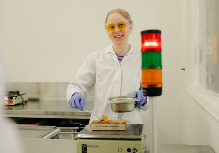 Eine Frau in hygienischer Schutzkleidung verpackt Lebensmittel.