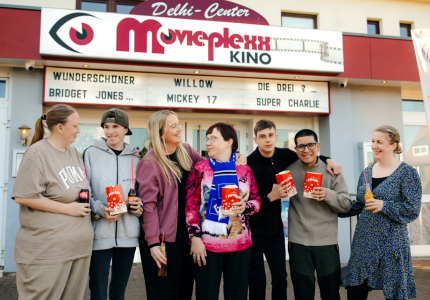 Eine Gruppe Menschen steht vor einem Kino
