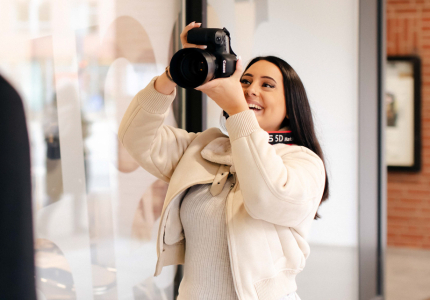 Eine junge Frau fotografiert mit einer Kamera.
