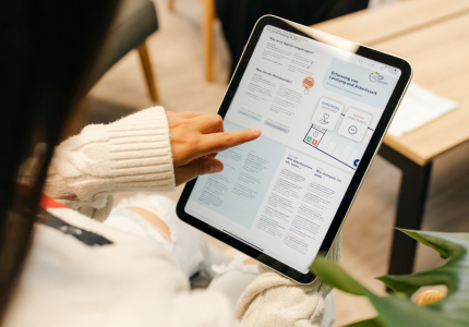 Eine Frau schaut sich auf einem Tablet einen Flyer der Lebenshilfe an. 