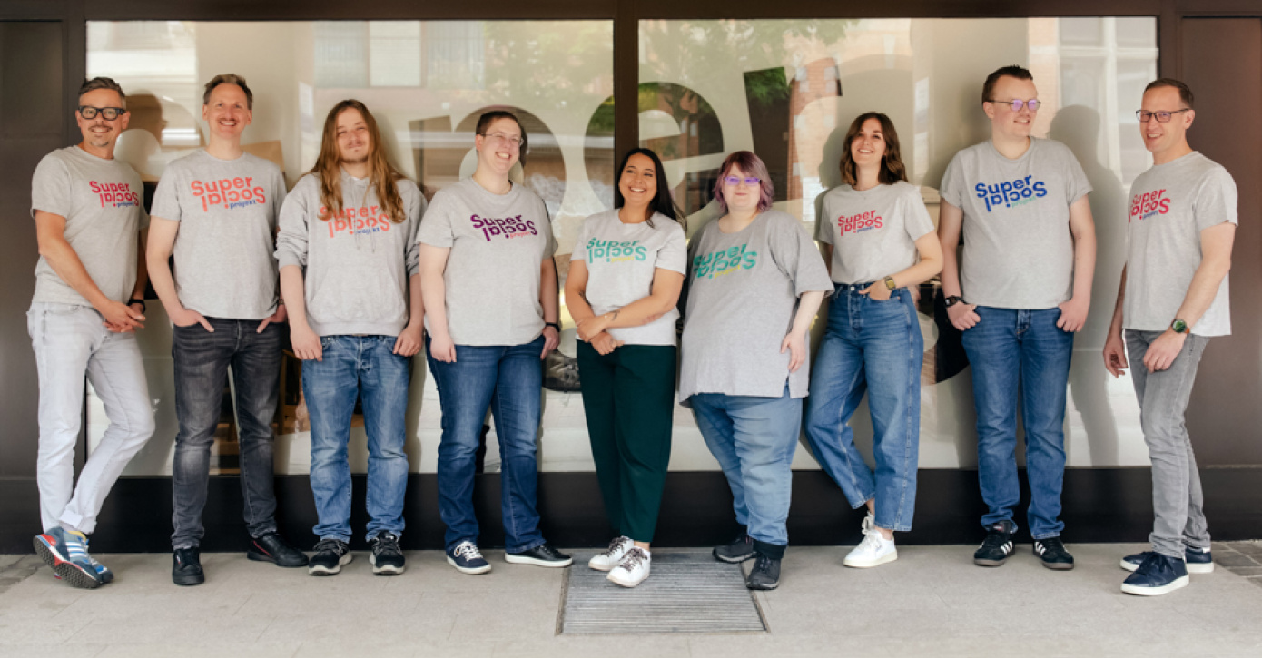 Gruppenfoto des Super Social Teams. Alle tragen ein graues T-Shirt mit dem Schriftzug SuperSocial.