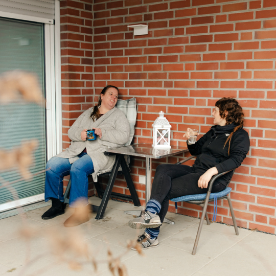 Zwei Frauen sitzen auf der Terrasse und trinken Kaffee