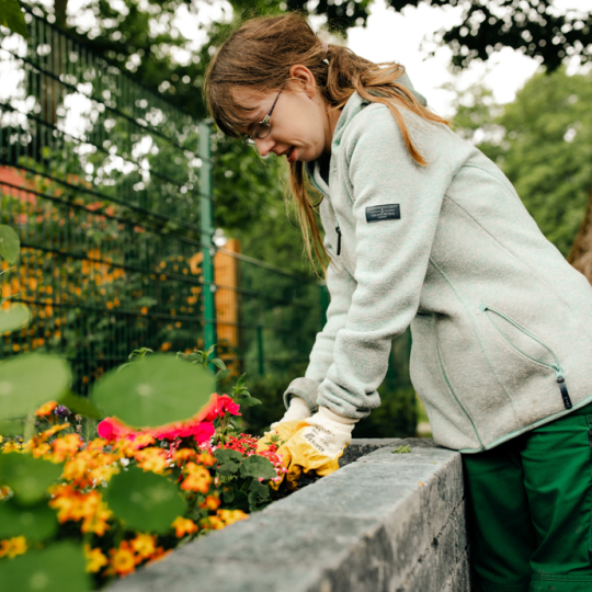 Eine junge Frau pflanzt Blumen in ein Blumenbeet.